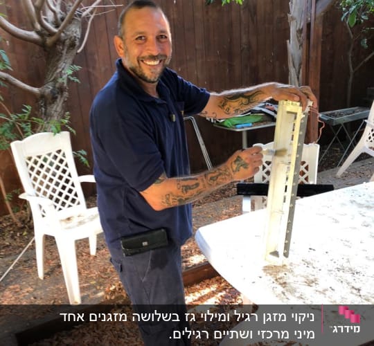 אדם מחזיק חלק ממזגן על שולחן בחוץ